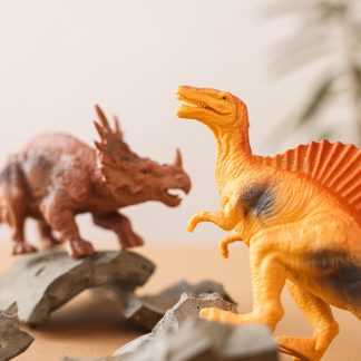 Close-up of dinosaur toys on a tabletop with broken shards, evoking prehistoric play.