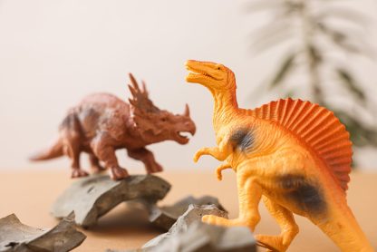 Close-up of dinosaur toys on a tabletop with broken shards, evoking prehistoric play.